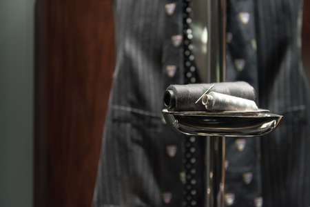 Needle and Thread on Stand with Suit Waistcoat and Tie in Background