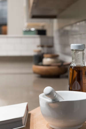 White Porcelain Pestle and Mortar Bowl with Assorted Cooking Accessories in Kitchen Sceneの写真素材