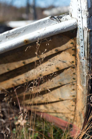 Old wooden dinghy rowboat beached on grass viewed close up on the prow with detail of the hull against a blue skyの写真素材
