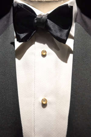 Close up on top part of tailored jacket on mannikin with black bow tie and sequined buttons on shirt