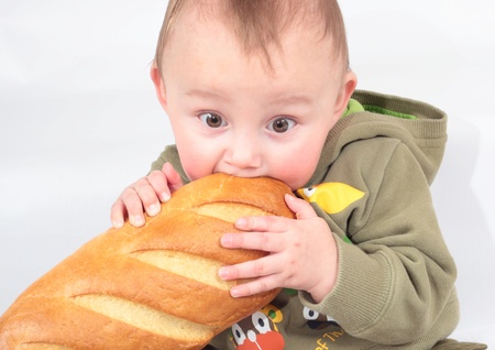 baby chewing a loaf of breadの写真素材