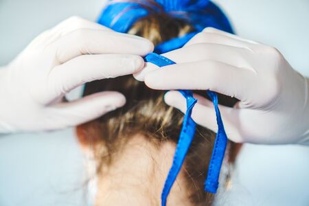 Healthcare professional tying surgical capの写真素材