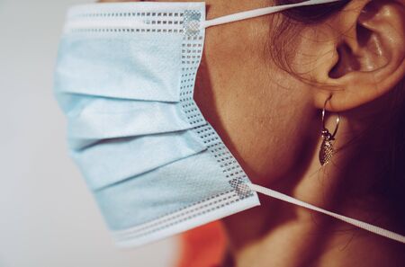 A woman putting on disposable surgical mask to prevent spreading of the viruses or contagion.の写真素材