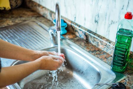 Woman washing her hands with soap in a hygienic way in her home sink. Kitchen