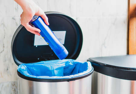 Girl throws a plastic container into the bin. A clear example of a recycling culture. For the health of the Earth.の写真素材