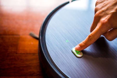 Turning on the robot vacuum cleaner. Modern technology for a connected and smart home. Autonomous,...