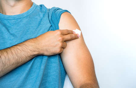 Boy holding the gauze on his shoulder with his hand, the place where he had just been given the dose...