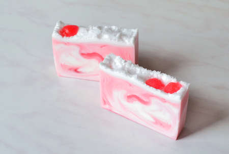 Two pieces of beautiful handmade strawberry soap, decorated with strawberriesの写真素材