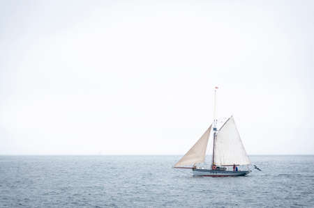 sailing boat on the sea sailing on the horizon there are two fishermen on it.