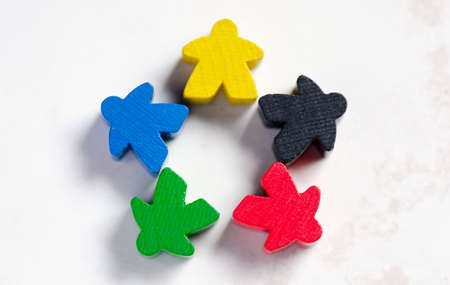 5 meeples of board games, they are in star formation. diversity concept. they are on a white marble...