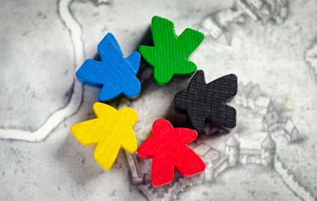 5 meeples of board games, they are in star formation, diversity concept. they are on a gray map background.の写真素材