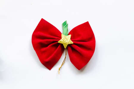 red christmas bow on white background, there is a star in the middle and a green ribbon.