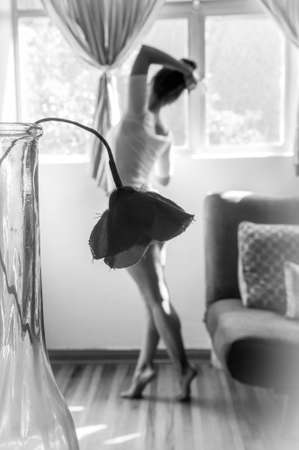 dancer in her living room in front of the window seen from the back, in front of her is a flower that seems to be her skirt.の写真素材