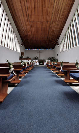 inside a church, you can see the cross in the background and the benches at the sides.の写真素材
