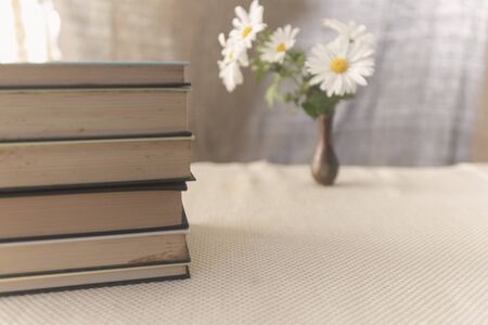 Old books on a table with a jar with flowers, daisies. Old fashioned, old styleの写真素材