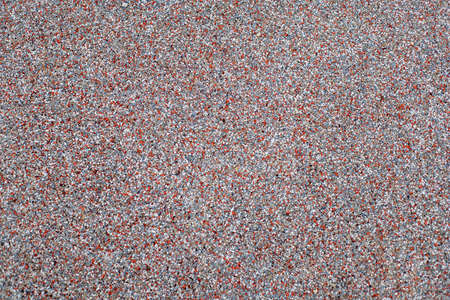 Photograph of a grainy texture on the floor of a children's playground. Outdoor texture and wallpaper. rubber flooringの写真素材