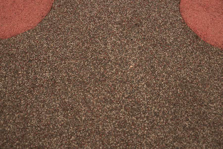 Photograph of a grainy texture on the floor of a children's playground. Outdoor texture and wallpaper. rubber flooringの写真素材