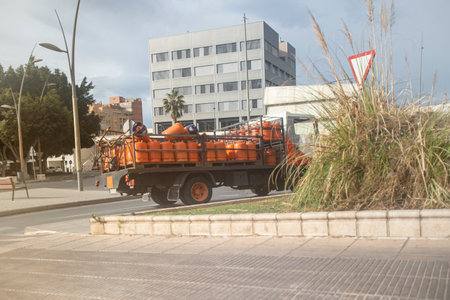Butane and propane gas are cleaner and more sustainable fuels than other energy sources, which contributes to the protection of the environment and the reduction of greenhouse gas emissions. Dynamic photograph of a truck transporting barrels of butane gas driving through the city. The powerful image showcases the essential role of energy transport in urban infrastructure. The truck, laden with cylindrical containers, navigates through city streets, symbolizing the distribution of vital energy resources. The city backdrop adds a sense of movement and urban connectivity, making this photograph suitable for projects related to energy, transportation, and city life.の写真素材