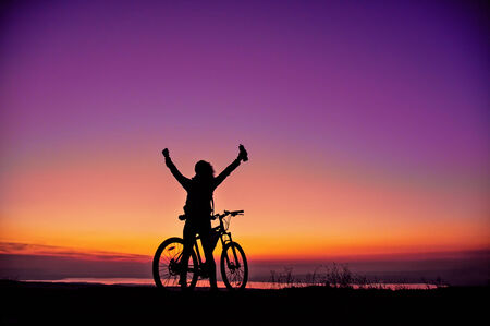 Girl with a bicycle watching the sunsetの写真素材