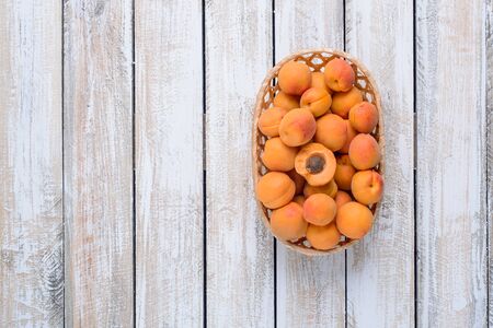Wicker basket with fresh apricots on a vintage wooden backgroundの写真素材