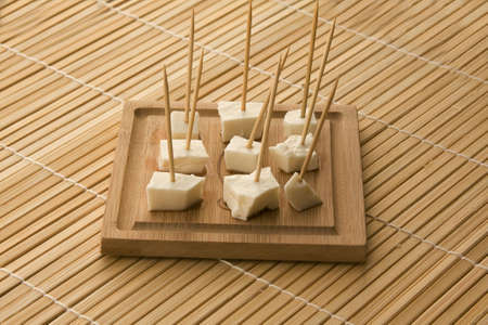 seved white cheese on a wooden board with toothpicsの写真素材