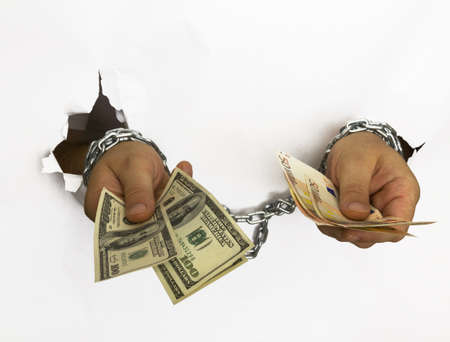 man's hand hancuffed in chains hold dollar and euro billsの写真素材