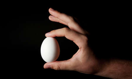 egg in one hand on black background
