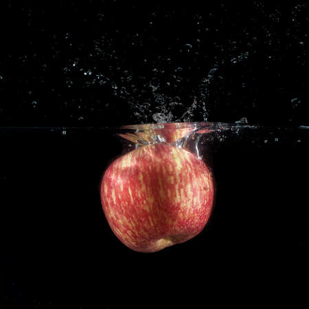 red apple dropped in fish tank filled with waterの写真素材