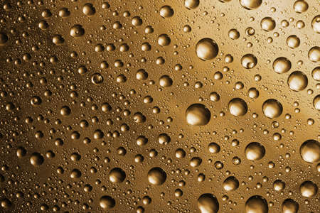 golden water drops on glass backgroundの写真素材