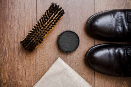 Brown leather shoes on a wooden floor with brush and creamの写真素材