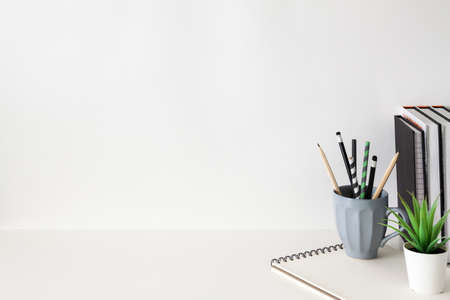 School desk against an empty white wall. Copy space. School supplies, books, succulent plant and notebook.の写真素材