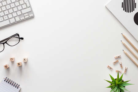 White office desk with copy space. Keyboard, notebook, glasses, pencils and succulent. View from...