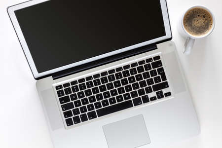 White office desk with a laptop. View from above. Coffee in a white mug.