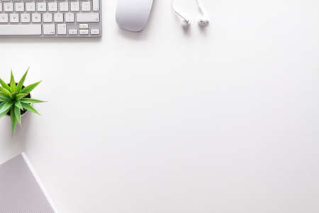 Top view of a white office desk. Copy space. White technology. Keyboard, mouse, headphones and succulent. White on white. Copy spaceの写真素材