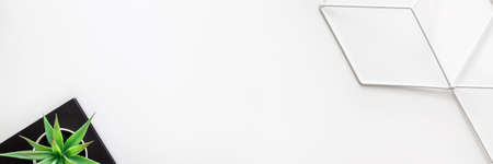 White desk. Top view copy space for text. Succulent on a black notebook and metal geometric toolbox. Hipster creative space. Scandinavian style. Panoramic real photoの写真素材