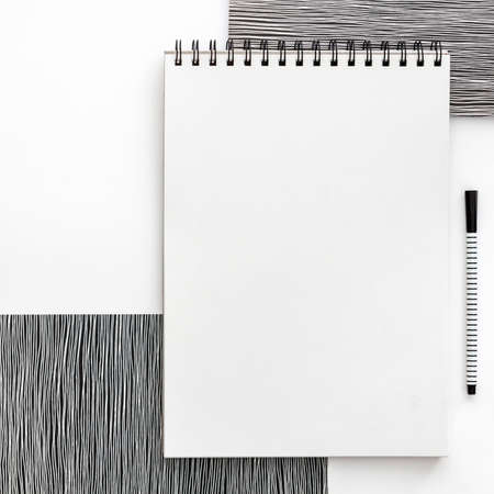 Blank spiral bound sketchbook with empty open page. Top view real photo. White background for text. Mockup. Black and white minimal conceptの写真素材