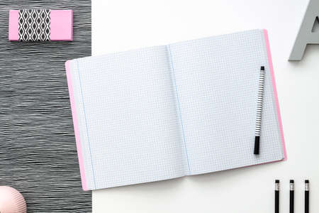 Blank notebook is open on modern white working table. Top view. Mockup with pastel pink elements. Black and white concept.の写真素材
