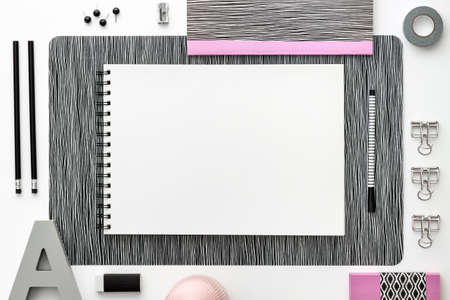 Open notebook, sketchbook or scrapbook with white blank page on the white table. Ideas, notes, plan writing or sketching concept. Top view mockup. Pastel pink office toolsの写真素材