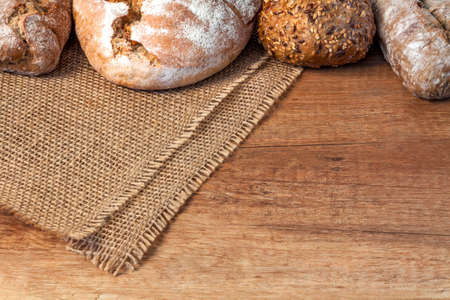 Wooden kitchen top with bread and rolls on a jute bag