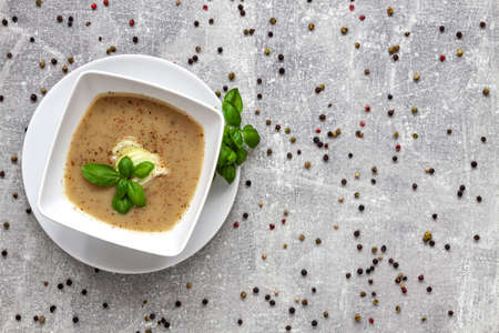 Onion soup, fresh basil and colored pepper on a concrete kitchen tableの写真素材