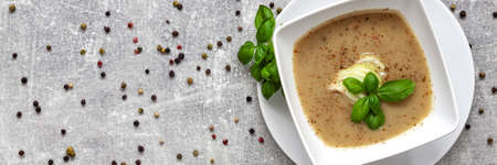 Panoramic view on onion soup, fresh basil and colored pepper on a concrete kitchen tableの写真素材