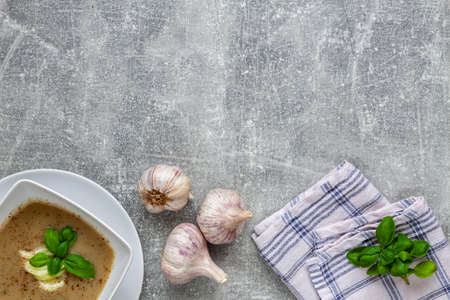 Garlic soup and fresh basil on a concrete kitchen tableの写真素材