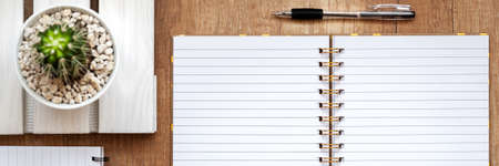 Panoramic view on wooden desk with open notebook, cactus and pen.の写真素材