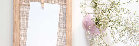 Panoramic photo with a wooden frame with a white card and a pink vase with sombre field flowersの写真素材