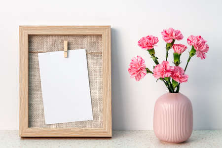 Terrazzo desk with wooden frame mockup and pink carnations in a notched vaseの写真素材