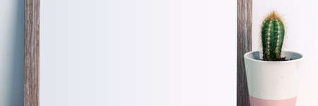 Cactus in a pink patterned pot and wooden copy space frameの写真素材