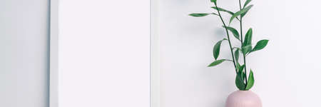 Panoramic photo of a white frame mockup with a pink notched vase with twigs with green leaves on an empty white backgroundの写真素材