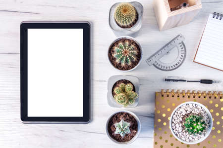 Top view on a wooden desk with a tablet, cactuses, a notebook, spiral notebook with golden dotsの写真素材
