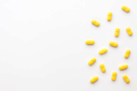 Yellow pills scattered on a white background. Copy space.の写真素材