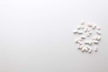 White pills scattered on a white background. Copy space.